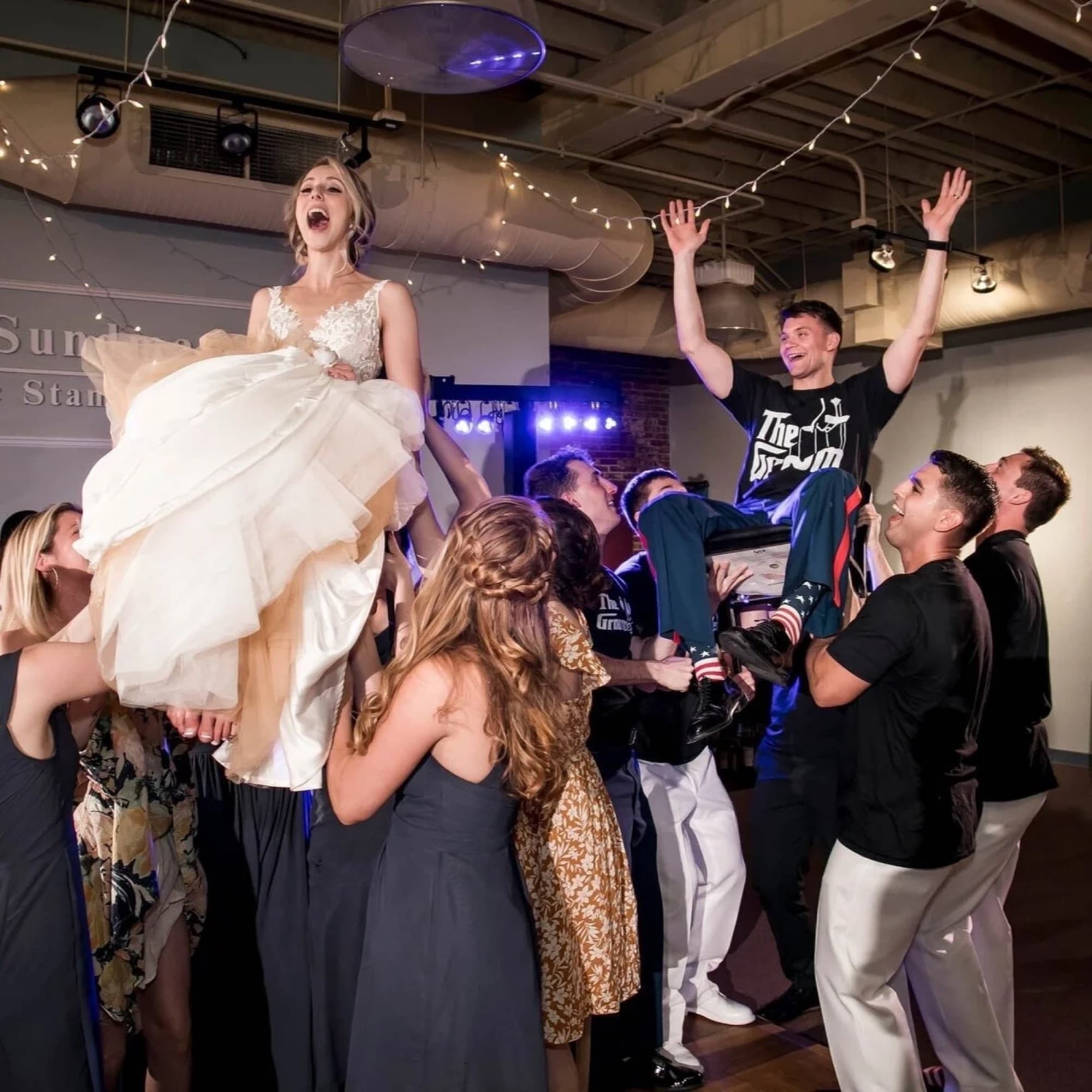 Bride lifted by guests on a packed dance floor