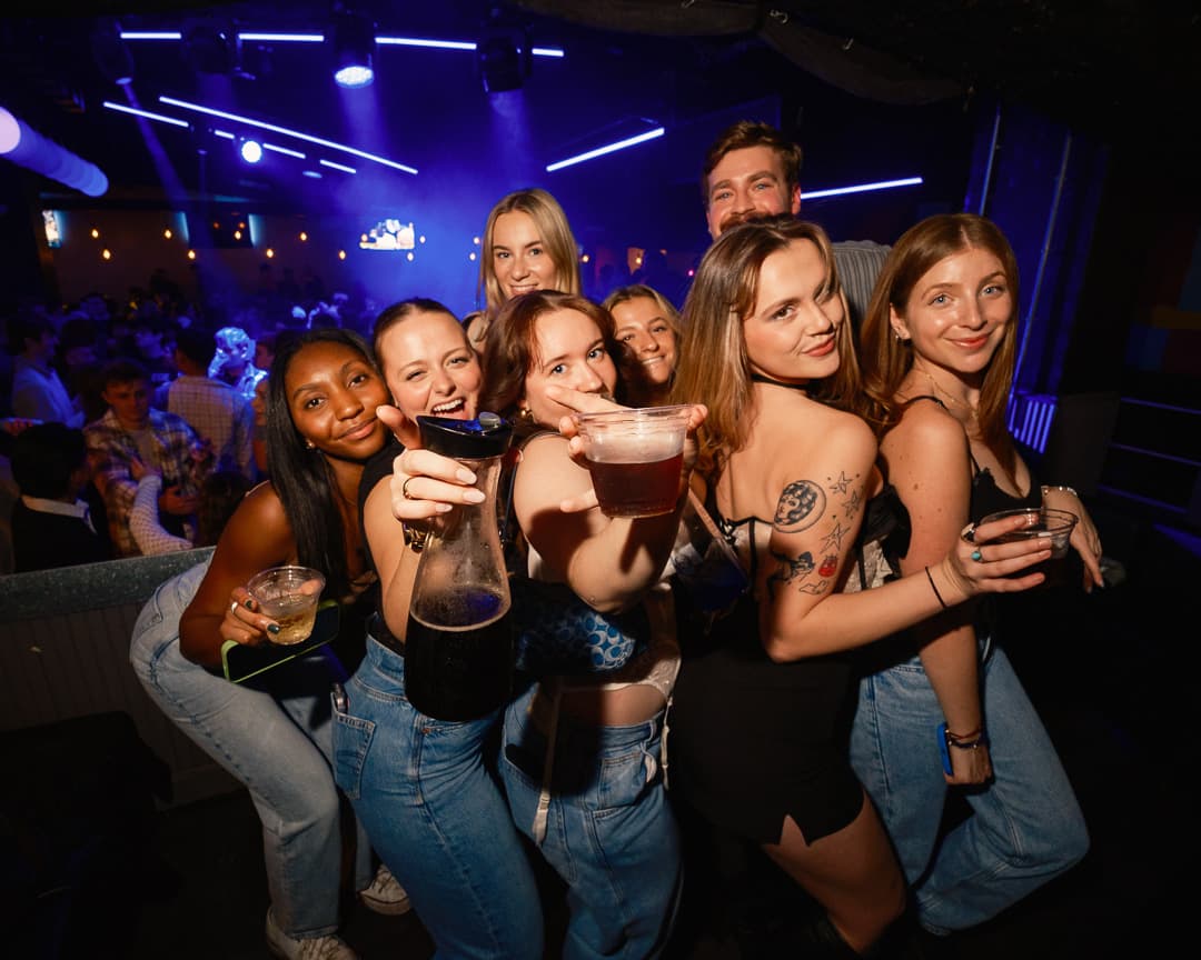 Friends celebrating together beside a busy nightclub dance floor