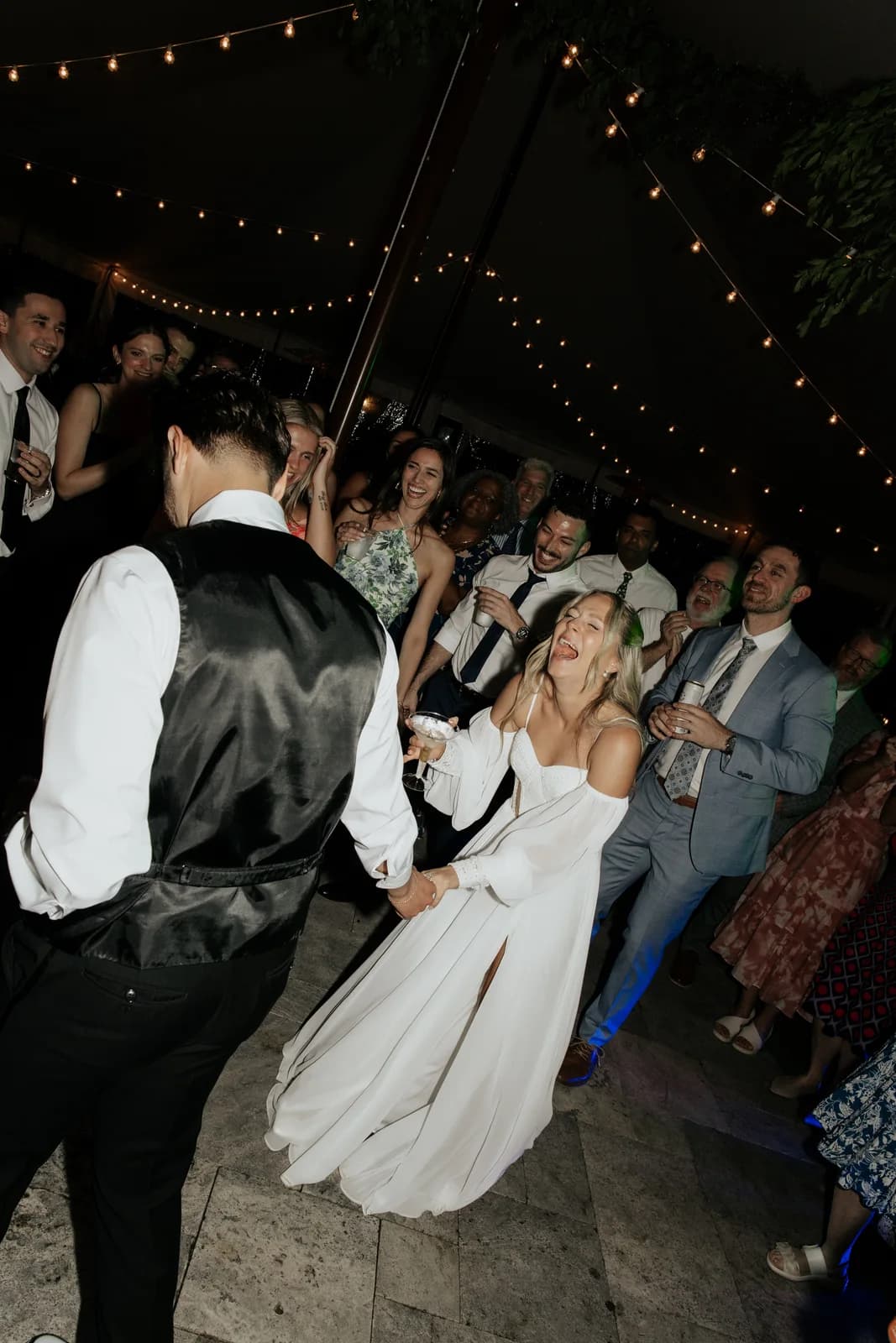Newlyweds dancing with their guests under string lights at Cypress House